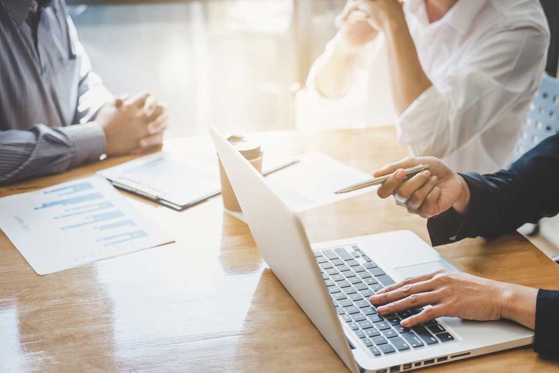 Beratungsgespräch am Schreibtisch mit Unterlagen und Laptop